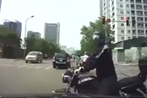 Chen ngang trước mũi ô tô, người đi môtô đưa kí hiệu lạ với tài xế