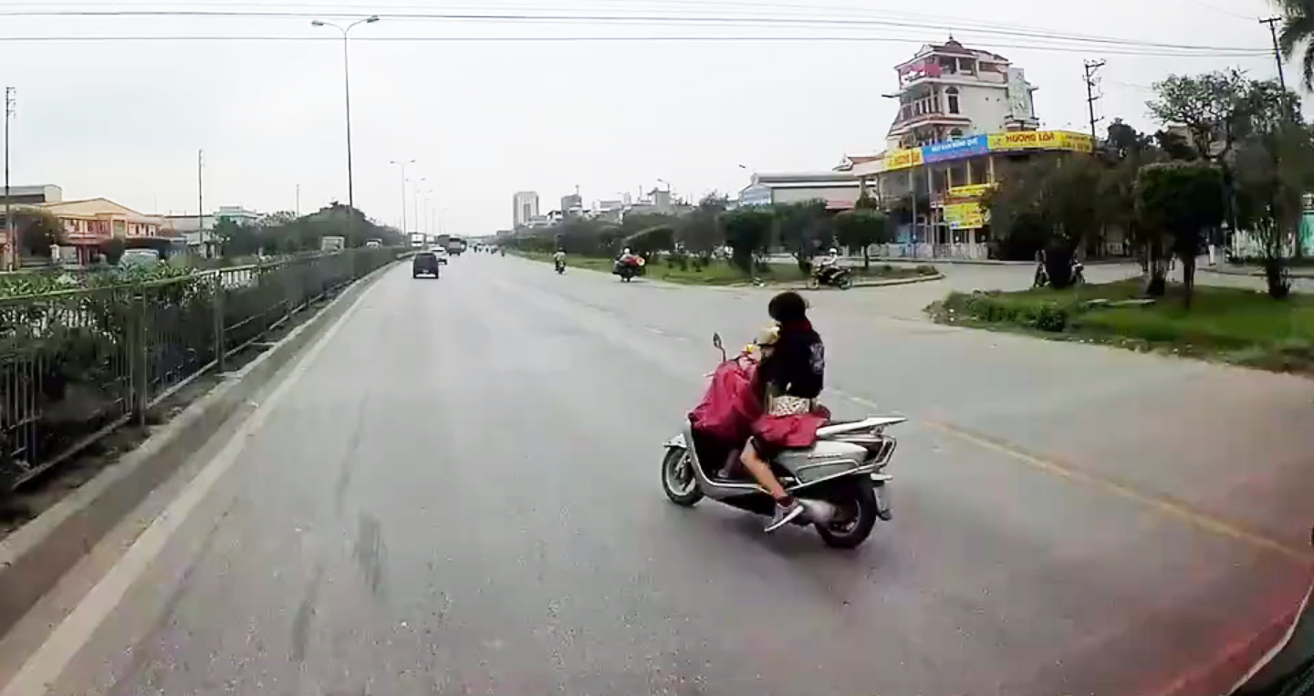 Nữ 'ninja' buông tay lái cởi áo mưa dù đang chở con nhỏ