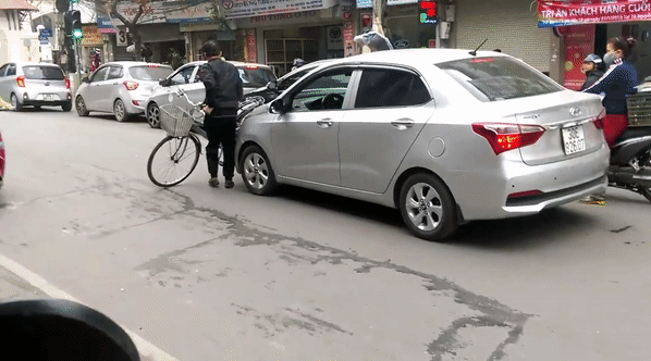 Người đàn ông vác xe đạp chặn đầu ô tô, xe cứu thương