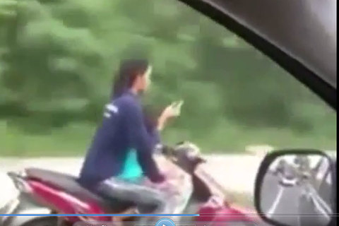Người phụ nữ chở trẻ em, buông 2 tay để sử dụng điện thoại