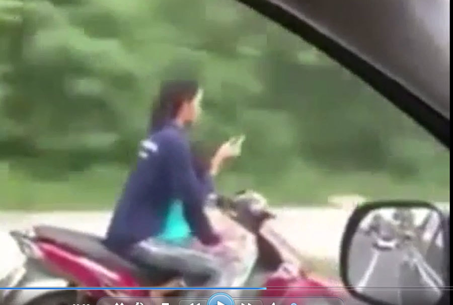 Người phụ nữ chở trẻ em, buông 2 tay để sử dụng điện thoại