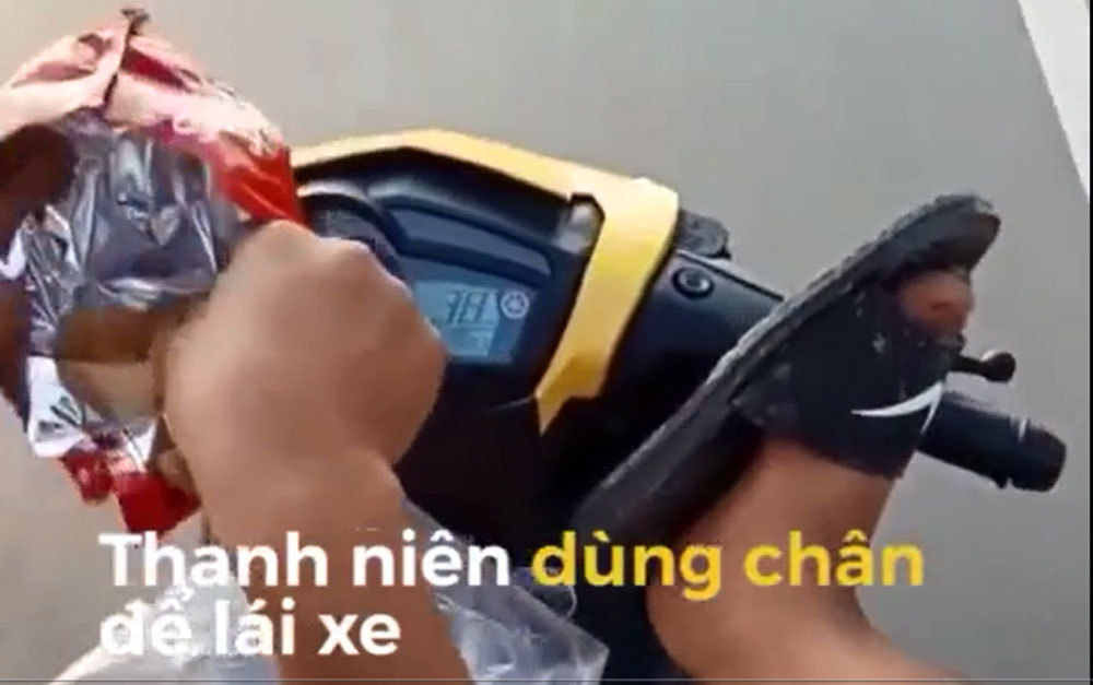 Thanh niên dùng chân lái xe, còn tay bốc bánh snack