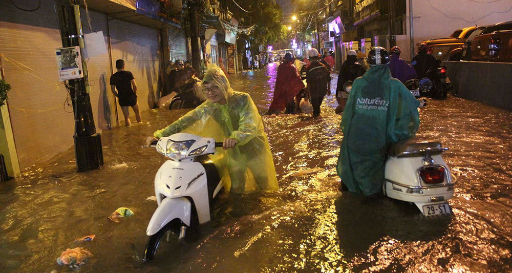 Người Hà Nội đội mưa sầm sập, rùng mình lội nước ngập rác về nhà