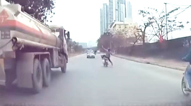 Vừa đi xe máy vừa dùng điện thoại, thanh niên suýt ngã vào xe bồn