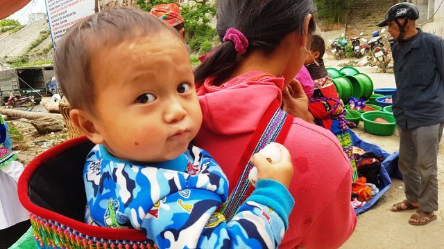 Children carried by mothers at Bac Ha Market