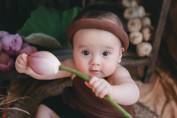 Hoa sen đang nở rộ, và em bé trên ảnh cũng đang rực rỡ cùng với nó. Cả hai tạo nên một hình ảnh thật tuyệt vời và đầy cảm hứng. Bạn chắc chắn sẽ thích bức ảnh này và thấy mình được tái sinh khi nhìn vào những bông hoa sen đó.