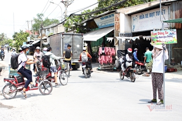 Bà U70 cầm biển giúp học sinh qua đường giữa nắng gắt Sài Gòn