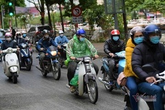 Giữa trưa, người Hà Nội vẫn mặc áo mưa tránh cái rét nhất từ đầu đông